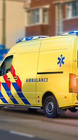 An ambulance vehicle driving in the road with its lights flashing