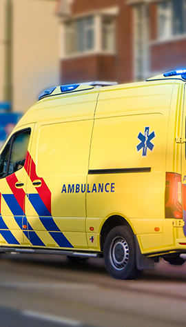 An ambulance vehicle driving in the road with its lights flashing