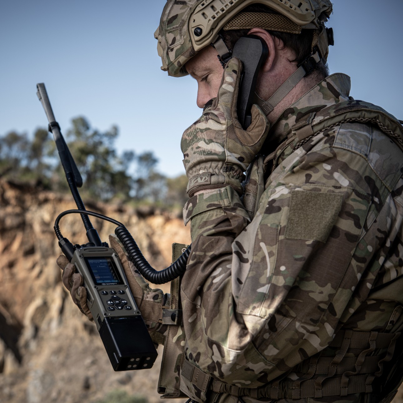 Barrett PRC-4080 transceiver with handheld receiver, used in the field by a military man in camouflage uniform