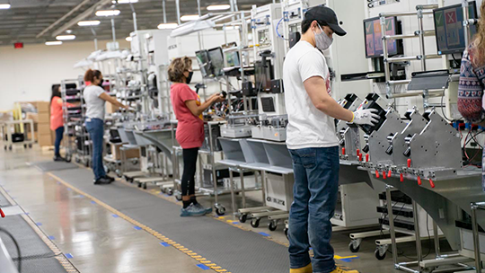 Four people on a manufacturing line, assembling devices