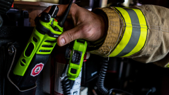 Firefighter in gear holding Motorola APX radios
