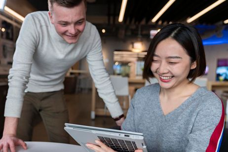 Three people looking at a laptop in a office 