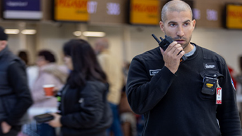 A Belgrade airport employee uses their radio in front of a left item of luggage 
