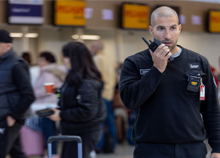 A Belgrade airport employee uses their radio in front of a left item of luggage 