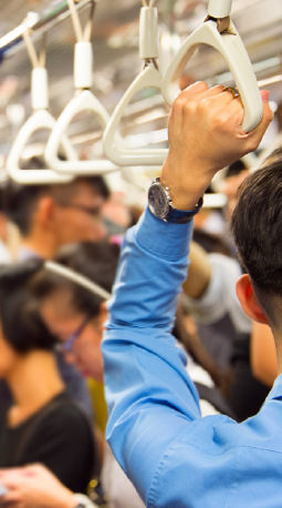 Passenger holding onto train handle, crowded train car