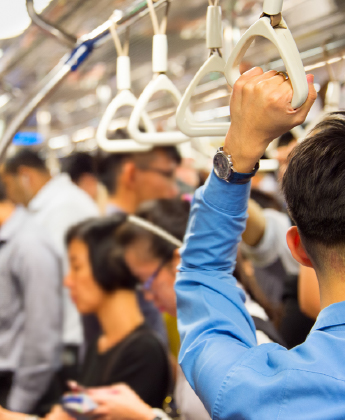 Passenger holding onto train handle, crowded train car