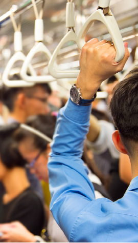 Passenger holding onto train handle, crowded train car