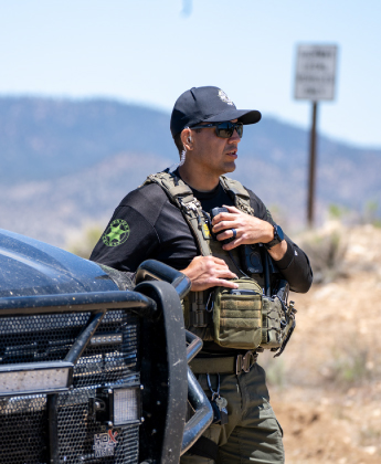 Police officer next to car holding on to a radio
