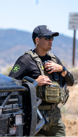 Police officer next to car holding on to a radio