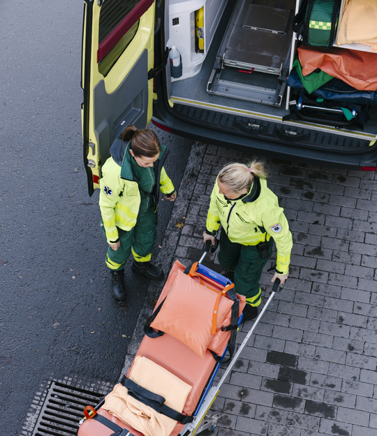 Two paramedics in uniform working together to carry a stretcher