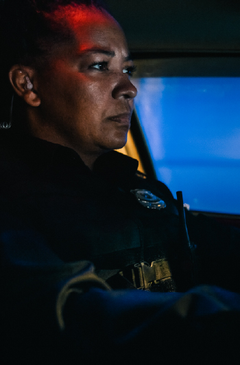 Police officer on patrol in a vehicle at night.