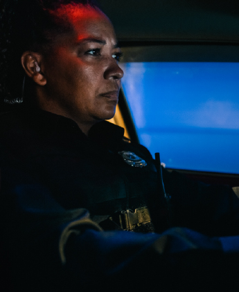 Police officer on patrol in a vehicle at night.