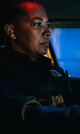 Police officer on patrol in a vehicle at night.