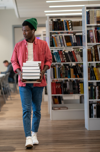 Student carries books through a library