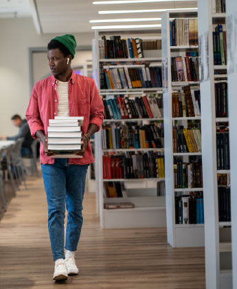 Student carries books through a library
