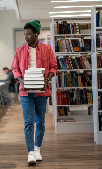 Student carries books through a library