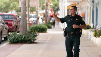 Image of a police officer walking down a city sidewalk