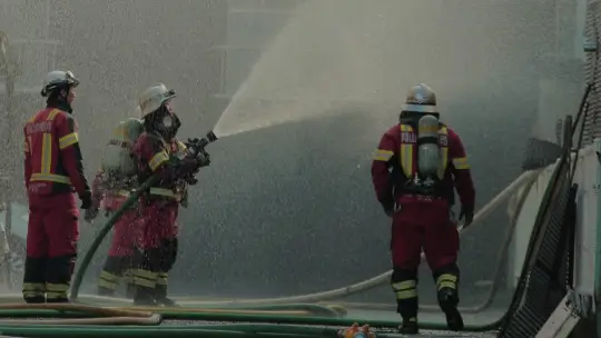Firefighters spraying down a building.