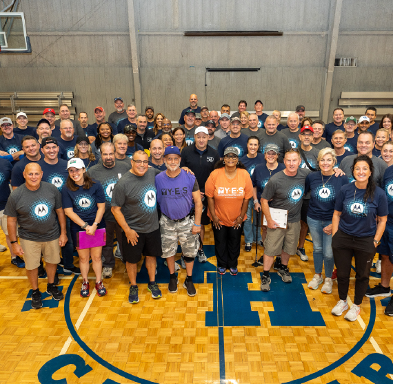 A group of people standing together on a basketball court.