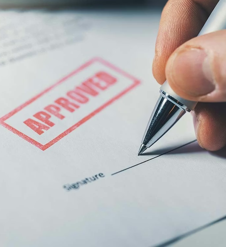 Man signing a piece of paper stamped "Approved"