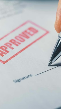 Man signing a piece of paper stamped "Approved"