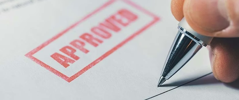 Man signing a piece of paper stamped "Approved"