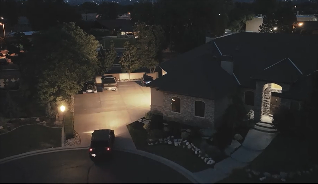 Image of house at night with car pulling into driveway.