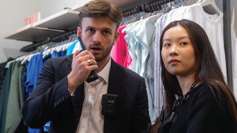 Retail employees standing side by side, employee on the left speaking in to radio
