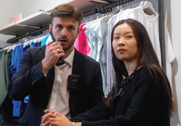Retail employees standing side by side, employee on the left speaking in to radio
