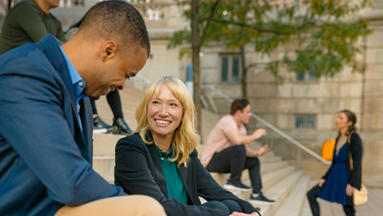 Man and woman sitting on outdoor cement staircase while talking