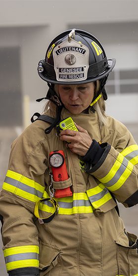 Image of woman firefighter next to red fire truck talking into a Motorola Solutions device