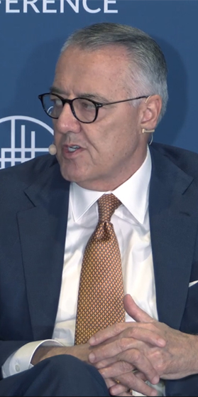 Image of MSI CEO, Greg Brown, sitting in a chair speaking on a Milken Institute Panel