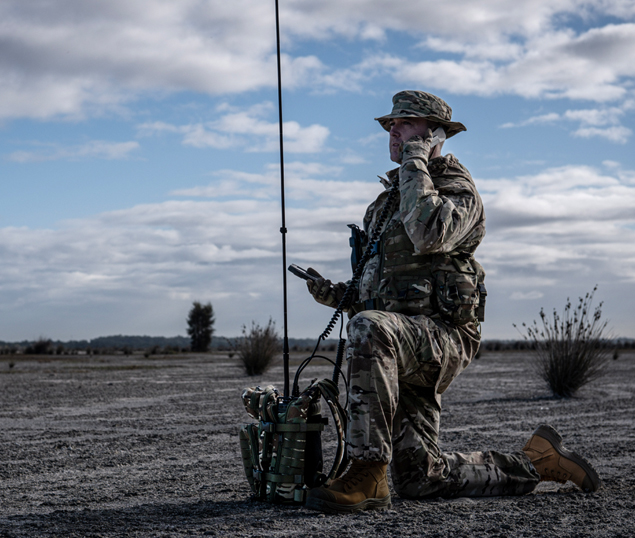 man in military uniform using manpack HF radio