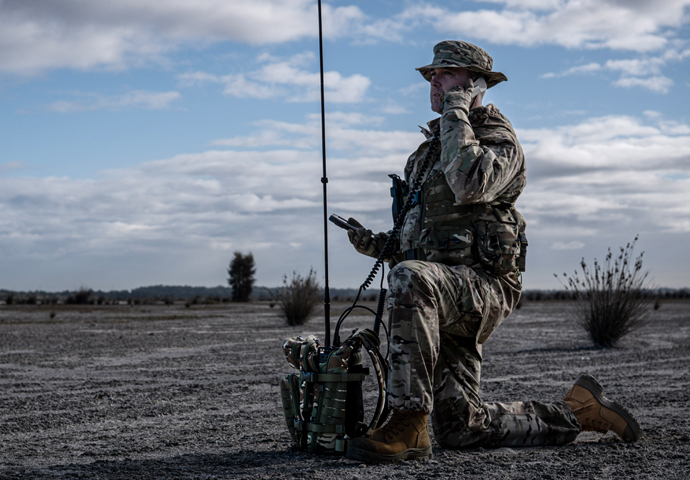 man in military uniform using manpack HF radio