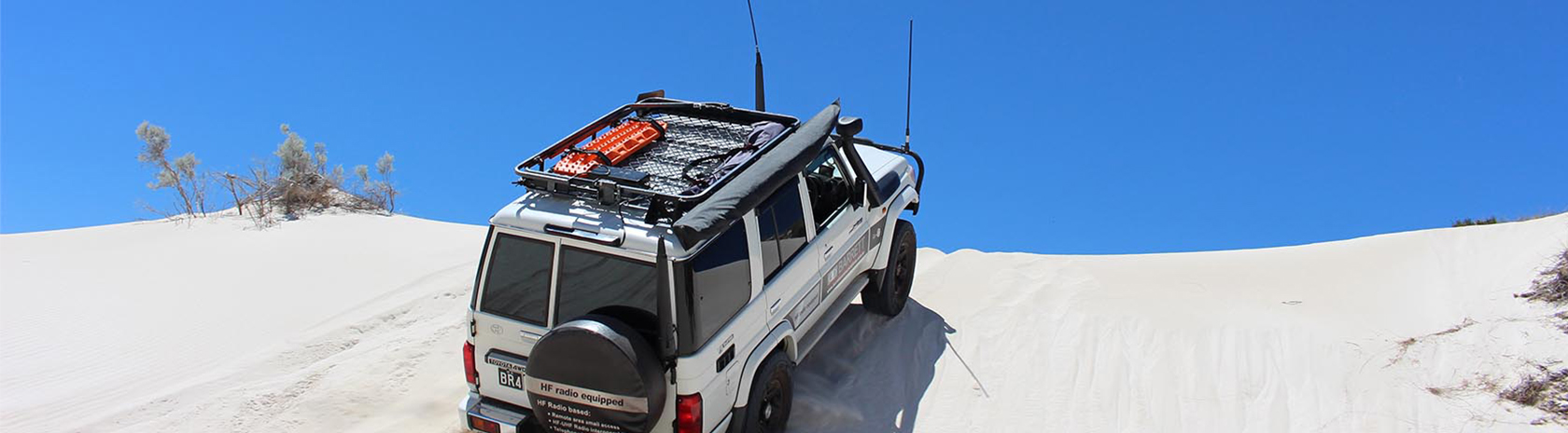 4x4 with large antennas driving up a sand dune