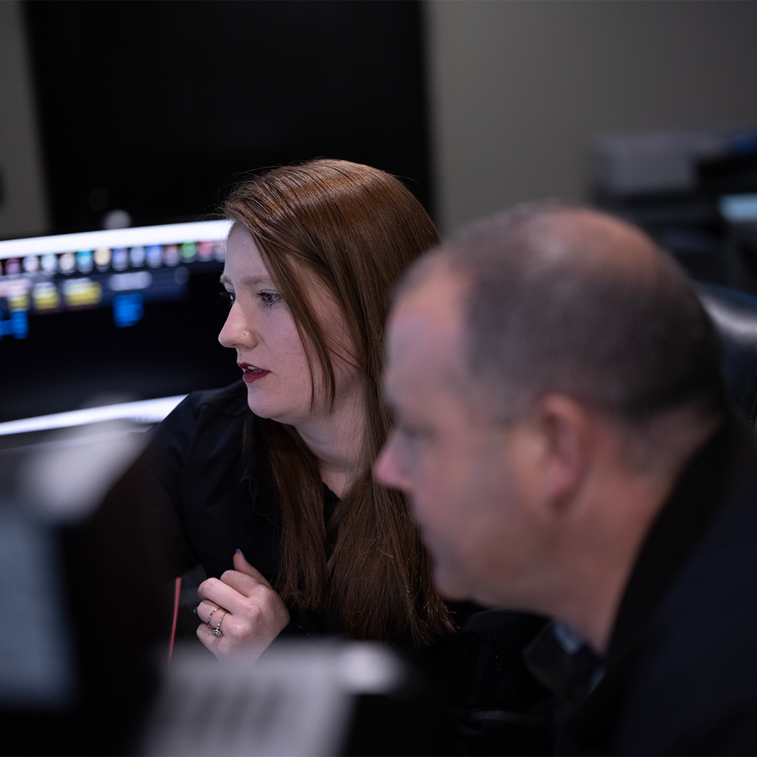 Two operators at a real-time crime center consult with each other to resolve an incident in progress