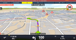 A screenshot of a turn-by-turn navigation map, likely from the Sygic application, showing a route from Sheffield Teaching Hospitals Foundation Trust, Royal Hallamshire Hospital in Sheffield to Charles Street, Leicester. The current location is on Charles Street, Leicester, and the next turn is a right turn onto Baron Street (A594) in 100 yards. The estimated time of arrival is 19:34, the remaining distance is 65 miles, and the remaining travel time is 1 hour and 37 minutes. The speed limit is shown as 30 mph, and several warning signs for roadworks or hazards are visible on the map. The map displays a 3D view of the city streets, including names like St Georges Way, Baron Street, Thumby, Bushby, Evington, Great Stretton, Great Glen, and Newton Harcourt.