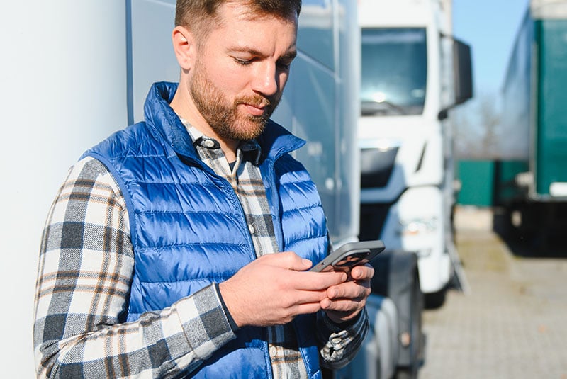 A lone worker using their smartphone to check in via a safety application (Theatro) while standing on a remote outdoor setting.