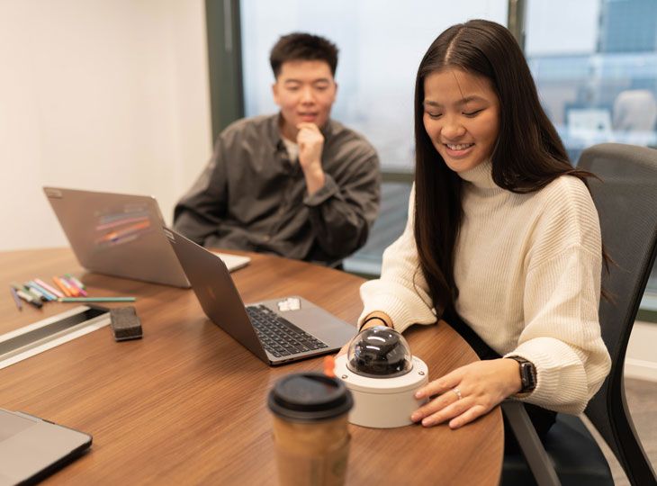 Two interns sitting at a table with a fixed video camera